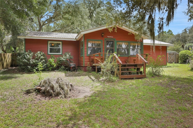 back of property featuring a deck and a lawn