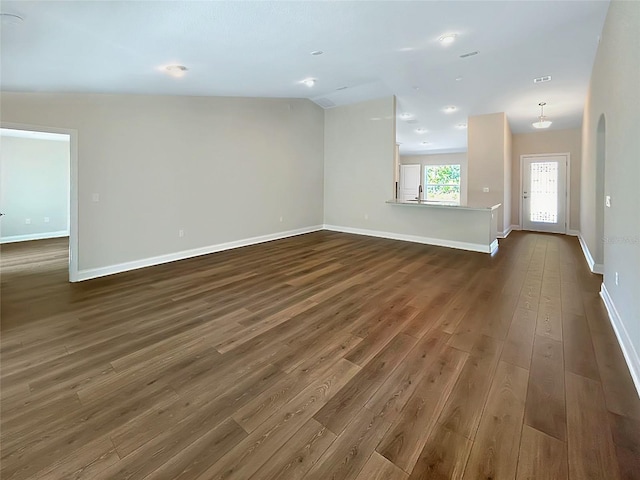 unfurnished living room featuring dark wood-type flooring and lofted ceiling