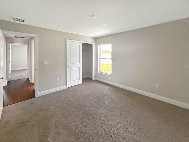 unfurnished bedroom with dark colored carpet and a closet