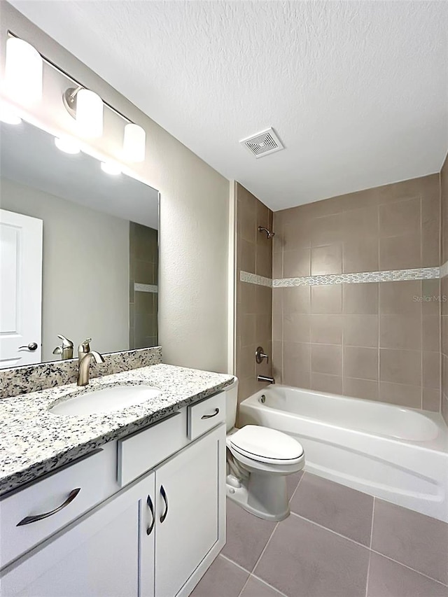 full bathroom with vanity, tiled shower / bath, tile patterned flooring, toilet, and a textured ceiling