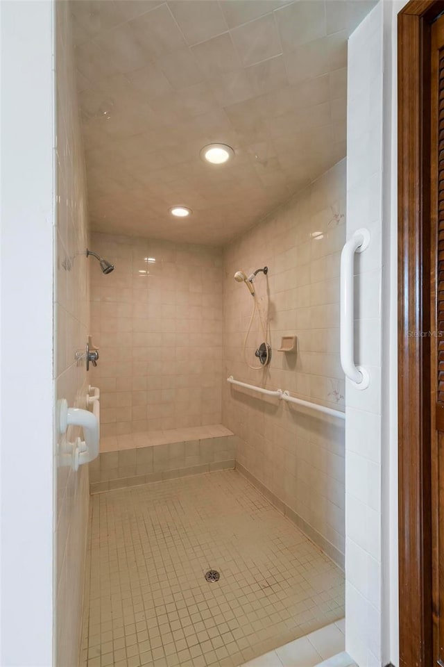 bathroom with tile patterned flooring and a tile shower