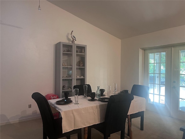 carpeted dining space with baseboards and vaulted ceiling