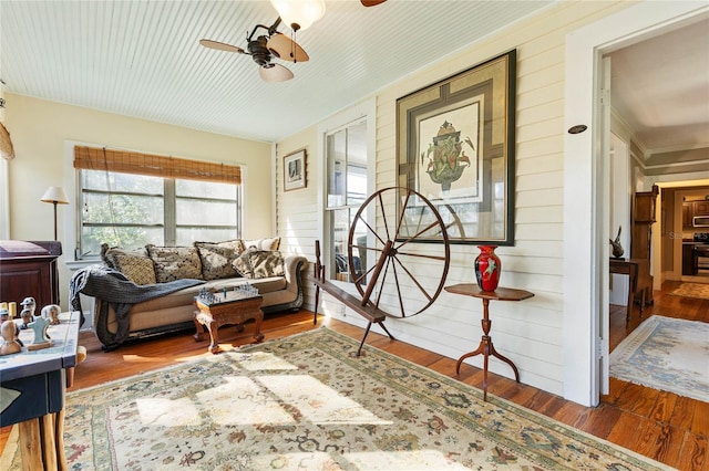 living room featuring hardwood / wood-style flooring, wooden walls, and ceiling fan