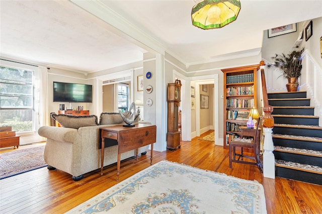 living room with wood-type flooring, ornamental molding, and plenty of natural light