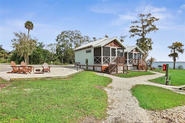 back of house featuring a water view, a sunroom, and a lawn