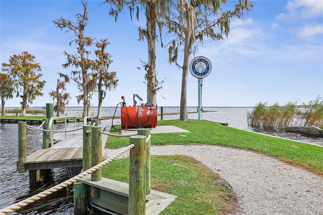 view of dock with a yard and a water view