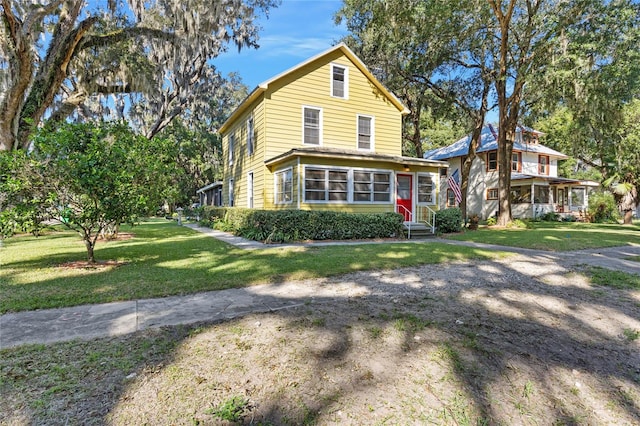 view of property featuring a front lawn and a sunroom