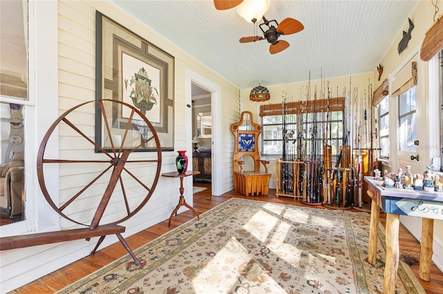 miscellaneous room with hardwood / wood-style floors, wooden walls, and ceiling fan