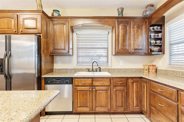 kitchen featuring appliances with stainless steel finishes, light tile patterned flooring, light stone countertops, and sink