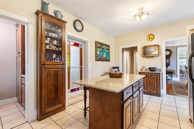 kitchen featuring light tile patterned flooring, a center island, a kitchen bar, and light stone counters