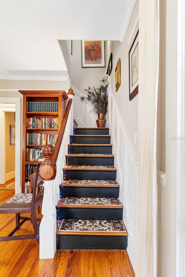 stairs featuring crown molding and hardwood / wood-style flooring