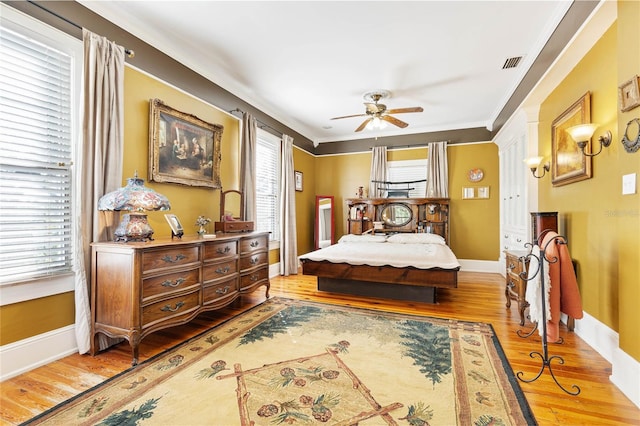 bedroom featuring multiple windows, wood-type flooring, and ceiling fan