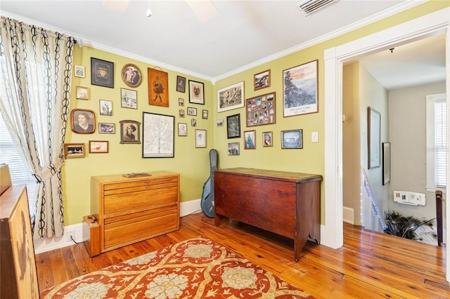 interior space with ornamental molding, wood-type flooring, and ceiling fan