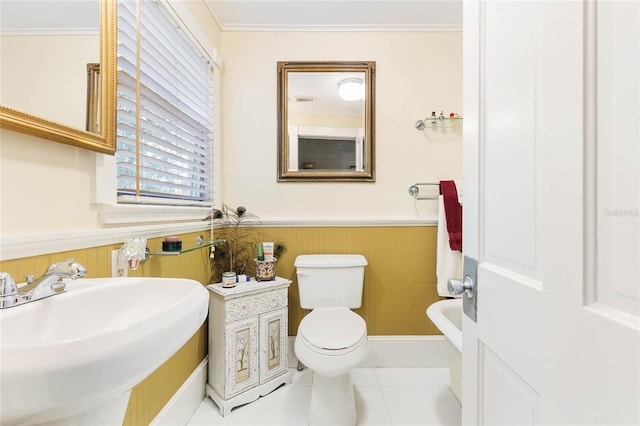 bathroom with wood walls, sink, toilet, crown molding, and tile patterned flooring