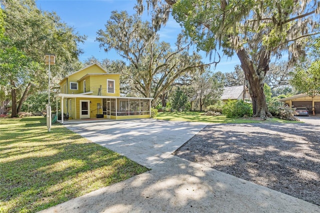 view of front of property featuring a sunroom, a front yard, and a carport