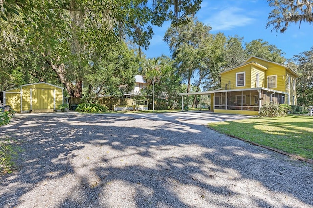 exterior space featuring a front yard, a carport, a shed, and a sunroom