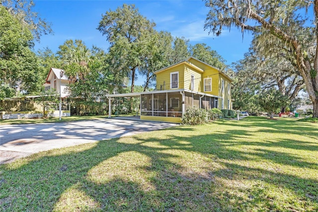 rear view of property featuring a yard, a carport, and a sunroom