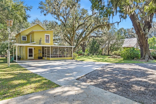 view of front of home with a sunroom and a front lawn