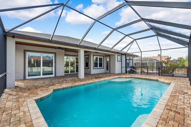 view of swimming pool featuring a patio area, glass enclosure, and ceiling fan