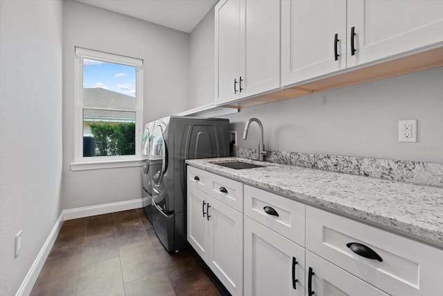 laundry room with independent washer and dryer, cabinets, sink, and dark tile patterned floors