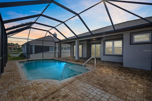 pool at dusk with a patio and a lanai