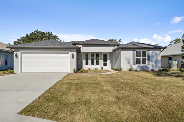 view of front of house with central air condition unit, a front lawn, and a garage