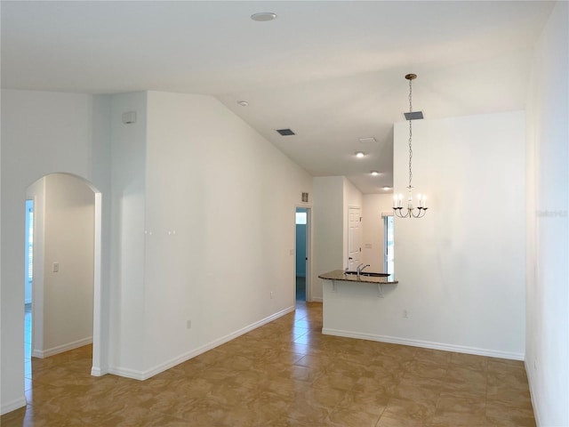 spare room featuring lofted ceiling and a chandelier