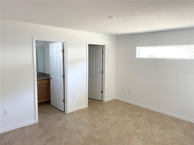 unfurnished bedroom with connected bathroom and a textured ceiling