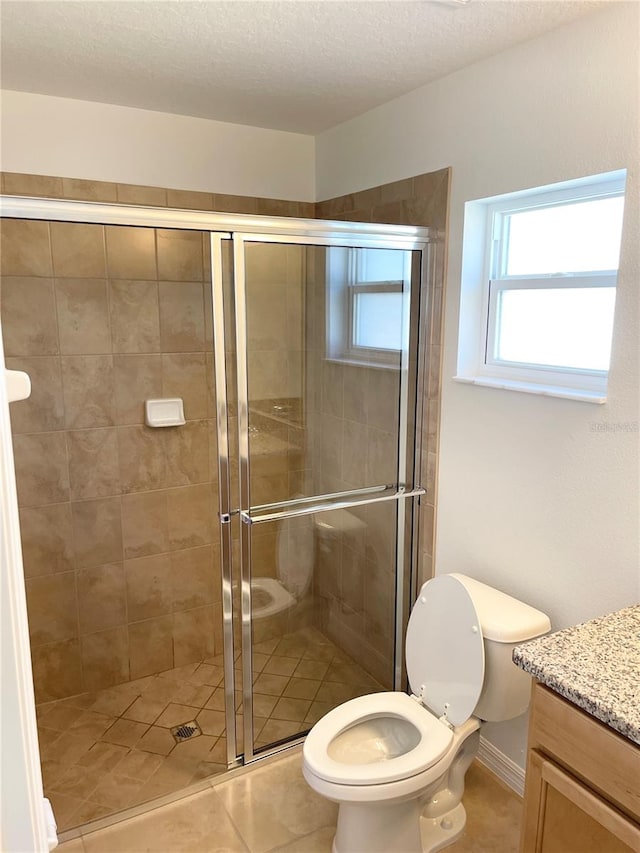 bathroom featuring vanity, a textured ceiling, tile patterned floors, walk in shower, and toilet