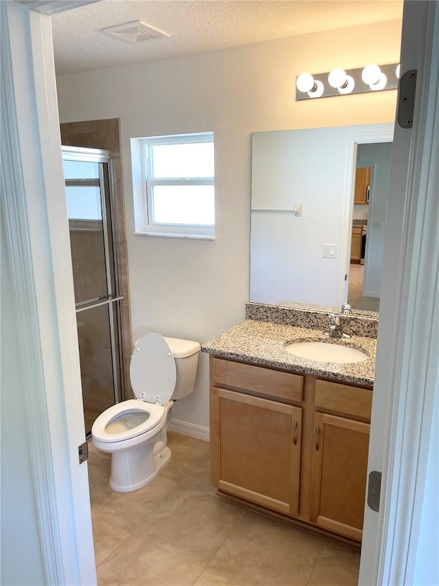 bathroom featuring vanity, tile patterned flooring, a textured ceiling, a shower with shower door, and toilet