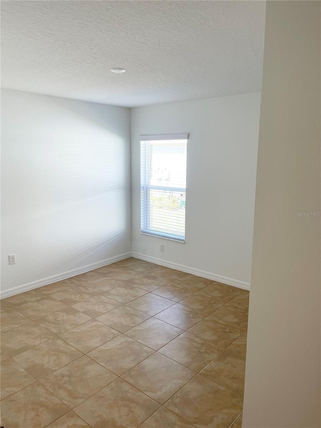 spare room featuring light tile patterned floors and a textured ceiling