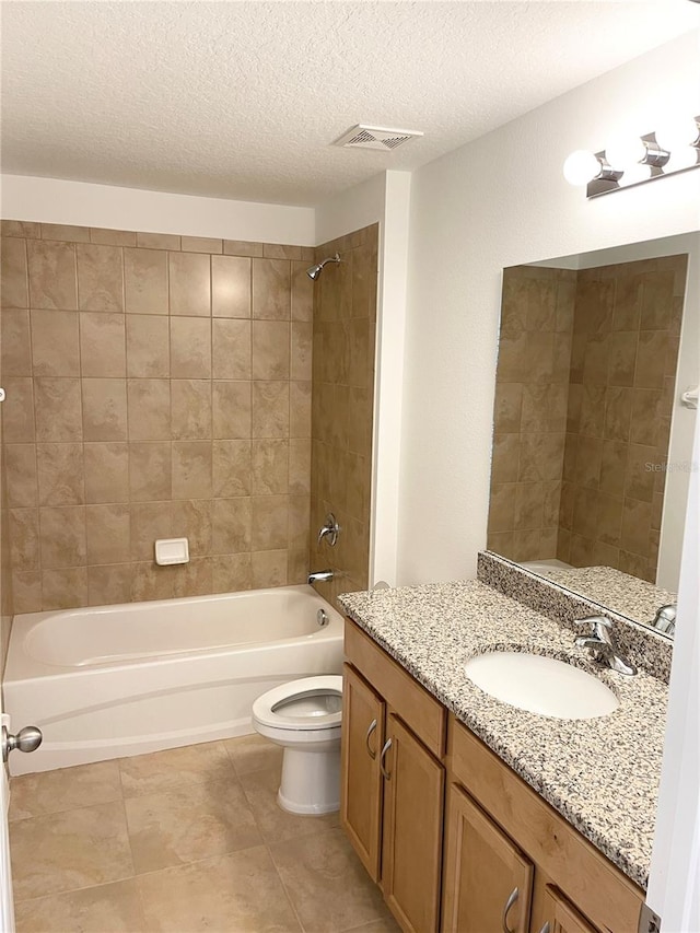 full bathroom with vanity, tiled shower / bath combo, tile patterned flooring, toilet, and a textured ceiling