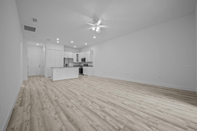 unfurnished living room with ceiling fan and light wood-type flooring