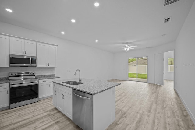 kitchen with light hardwood / wood-style floors, sink, a kitchen island with sink, white cabinetry, and appliances with stainless steel finishes