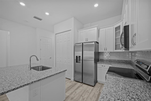 kitchen featuring appliances with stainless steel finishes, light stone countertops, sink, light hardwood / wood-style floors, and white cabinets