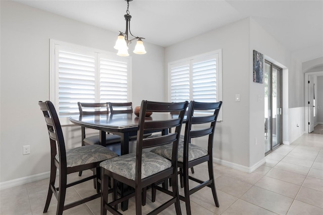 tiled dining space featuring a healthy amount of sunlight and a chandelier