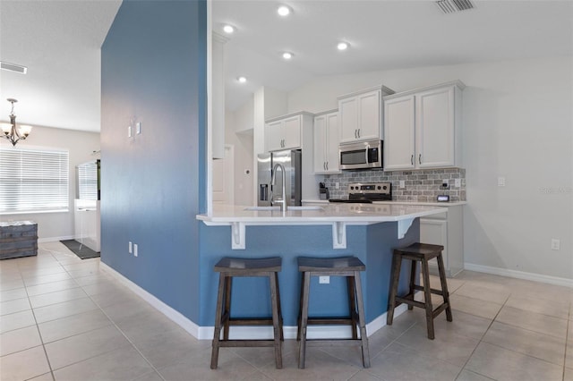 kitchen featuring a kitchen bar, stainless steel appliances, lofted ceiling, sink, and white cabinetry