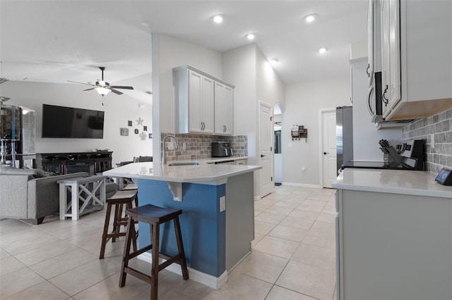 kitchen featuring white cabinetry, sink, black range oven, a breakfast bar area, and lofted ceiling