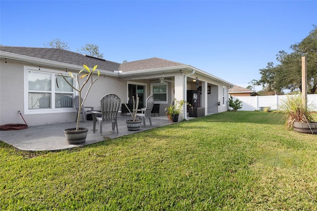 rear view of property featuring ceiling fan, a lawn, and a patio area