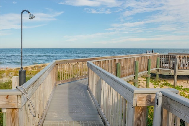 view of property's community featuring a deck with water view and a beach view