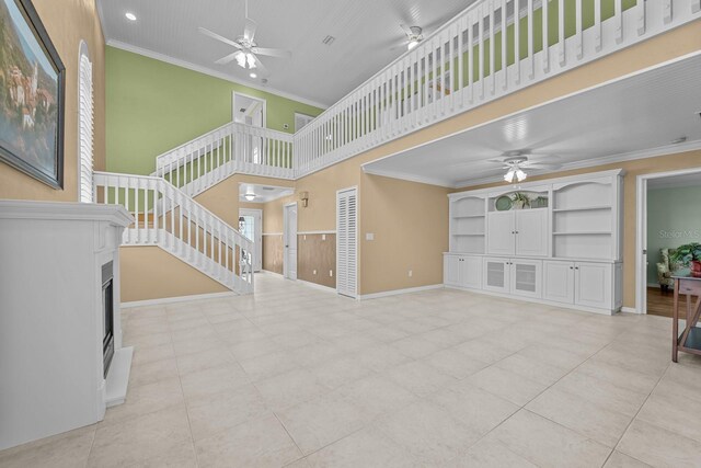 53 Sea Vista Dr, Palm Coast, FL 32137 - unfurnished living room with a ceiling fan, stairway, crown molding, a fireplace, and a high ceiling