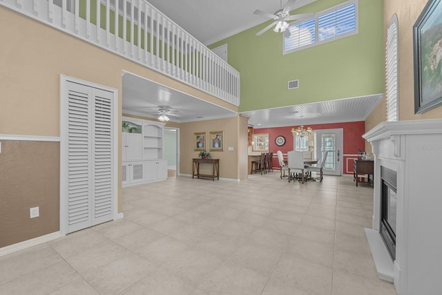 living room with ornamental molding, a high ceiling, ceiling fan with notable chandelier, and light tile patterned floors