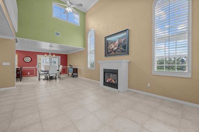 unfurnished living room featuring ornamental molding, light tile patterned floors, a high ceiling, and ceiling fan