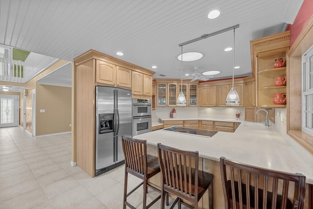 kitchen with sink, kitchen peninsula, stainless steel appliances, decorative light fixtures, and a breakfast bar area