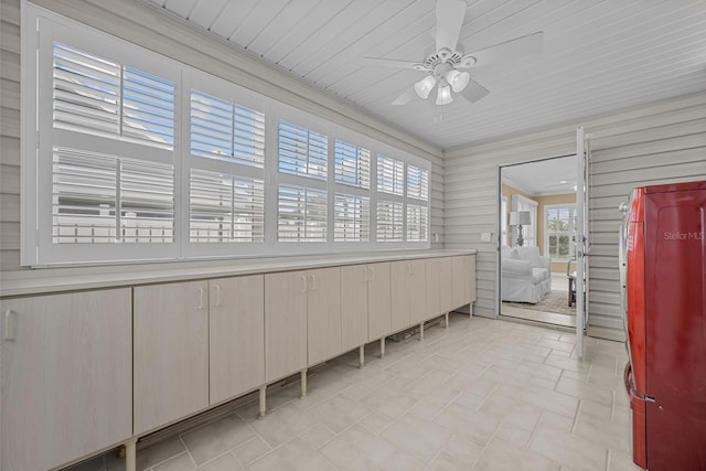 interior space featuring ornamental molding, wooden walls, and ceiling fan