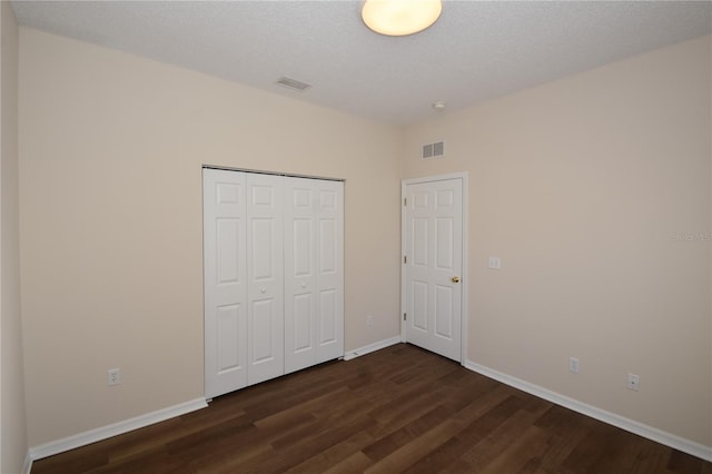 unfurnished bedroom with dark hardwood / wood-style floors, a closet, and a textured ceiling