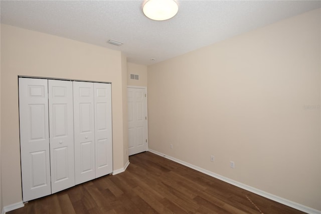 unfurnished bedroom with dark hardwood / wood-style floors, a closet, and a textured ceiling