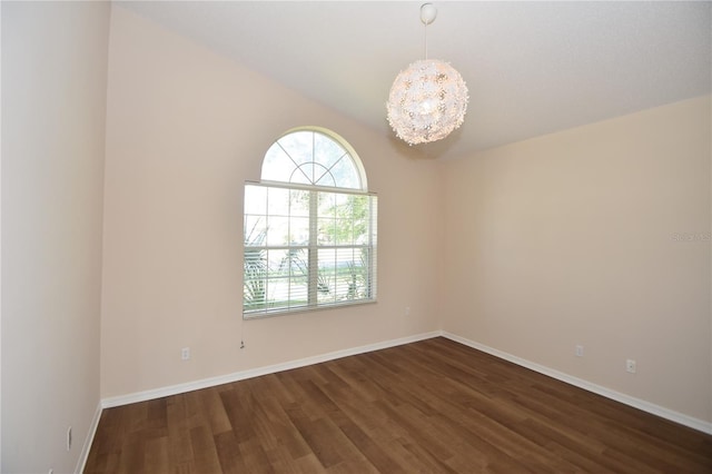 spare room featuring dark hardwood / wood-style flooring and a chandelier