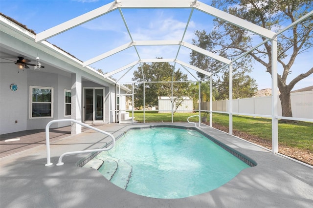 view of pool with a patio area, a yard, a lanai, ceiling fan, and a storage shed