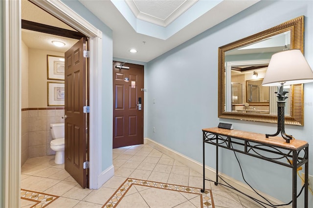 tiled foyer entrance with crown molding and a textured ceiling